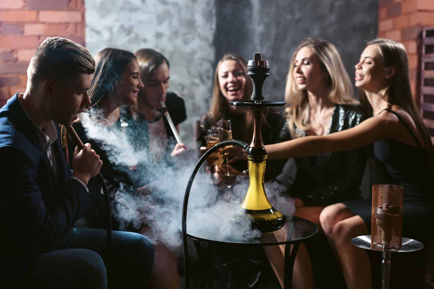 Pic: photo of several young people sitting around a table smoking shisha and drinking alcohol.