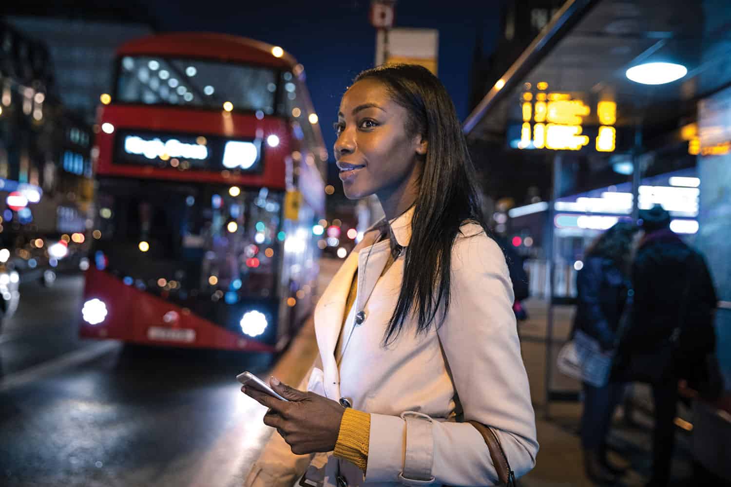 A young Black woman waiting for her bus home at night.