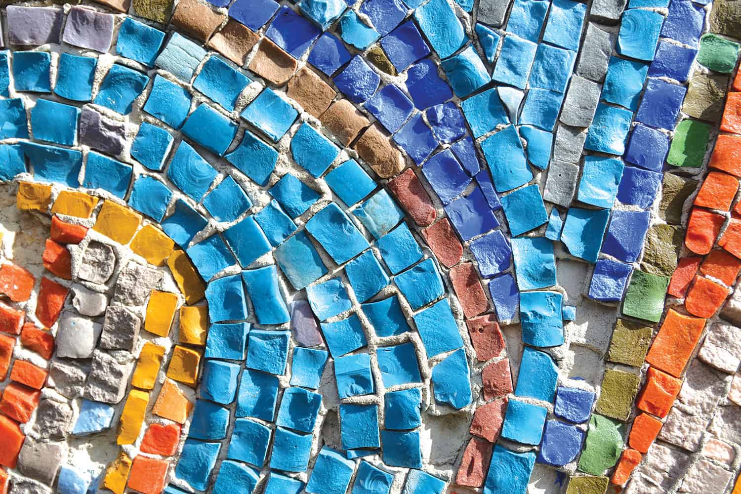 : close-up of mosaic of colourful stones set in grey filler – light and dark blue, orange, red, grey, green,yellow
