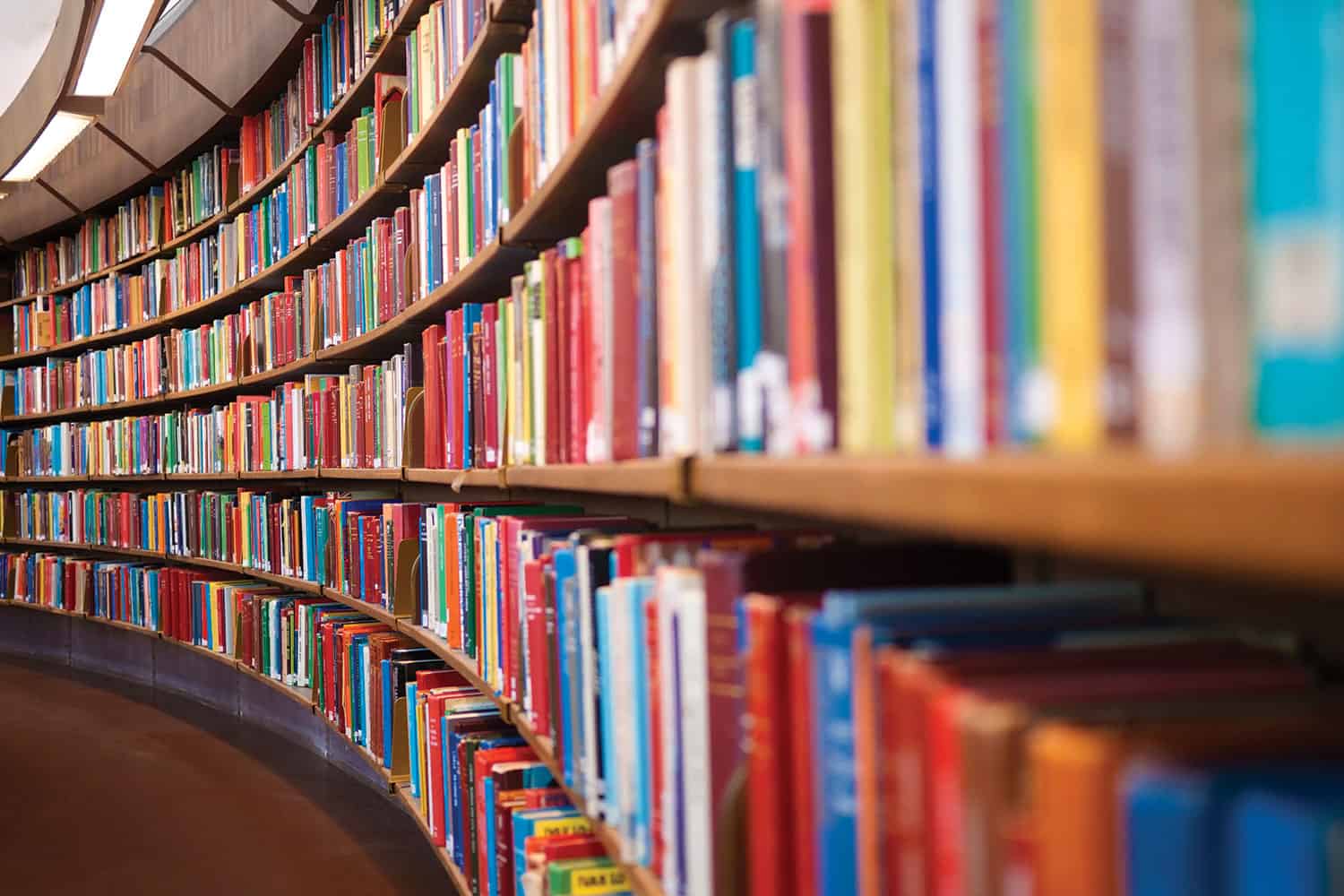 photo of library bookshelves packed with books curving away from the viewer