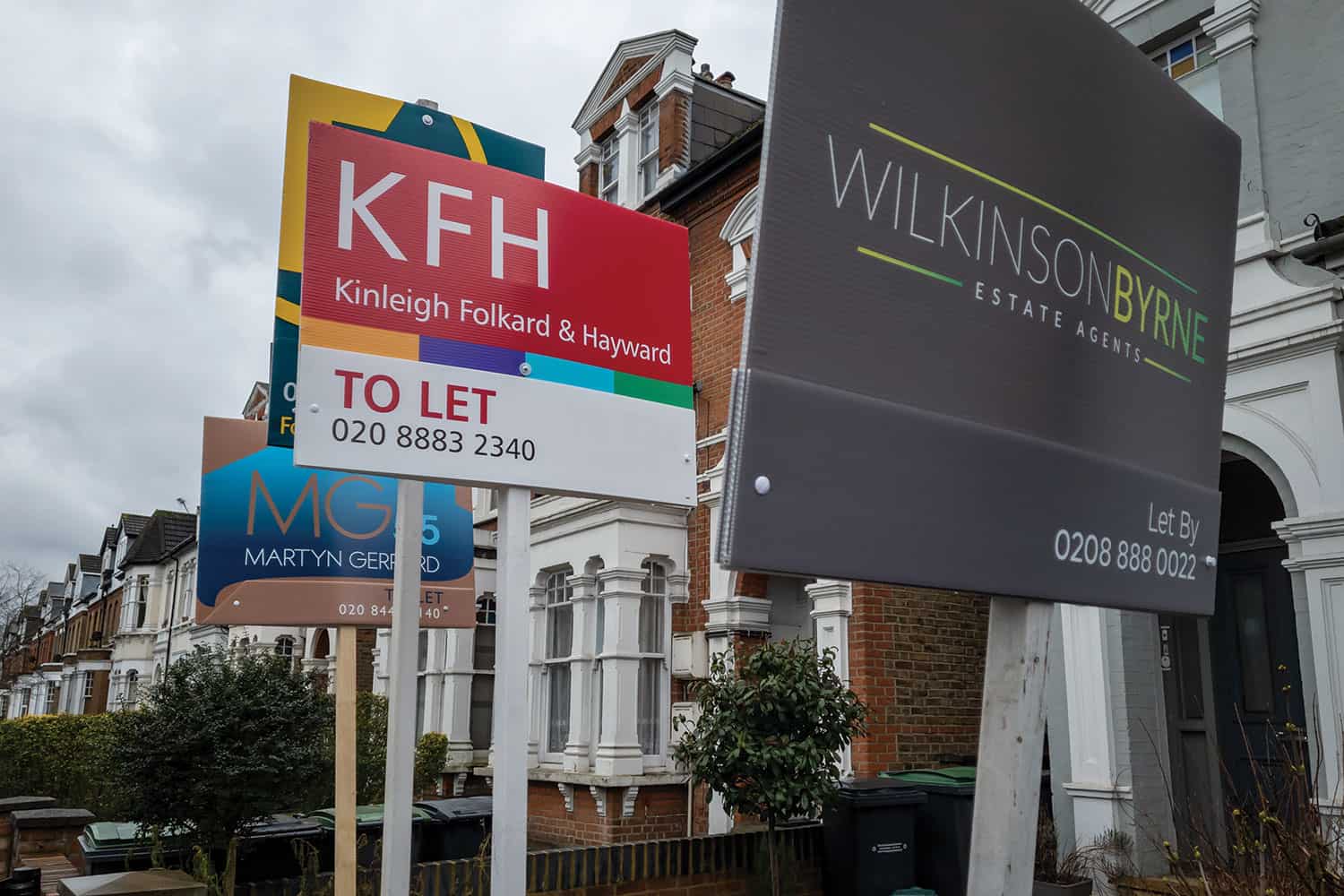 photo of different estate agents’ ‘to rent’ signs outside a terraced house in London