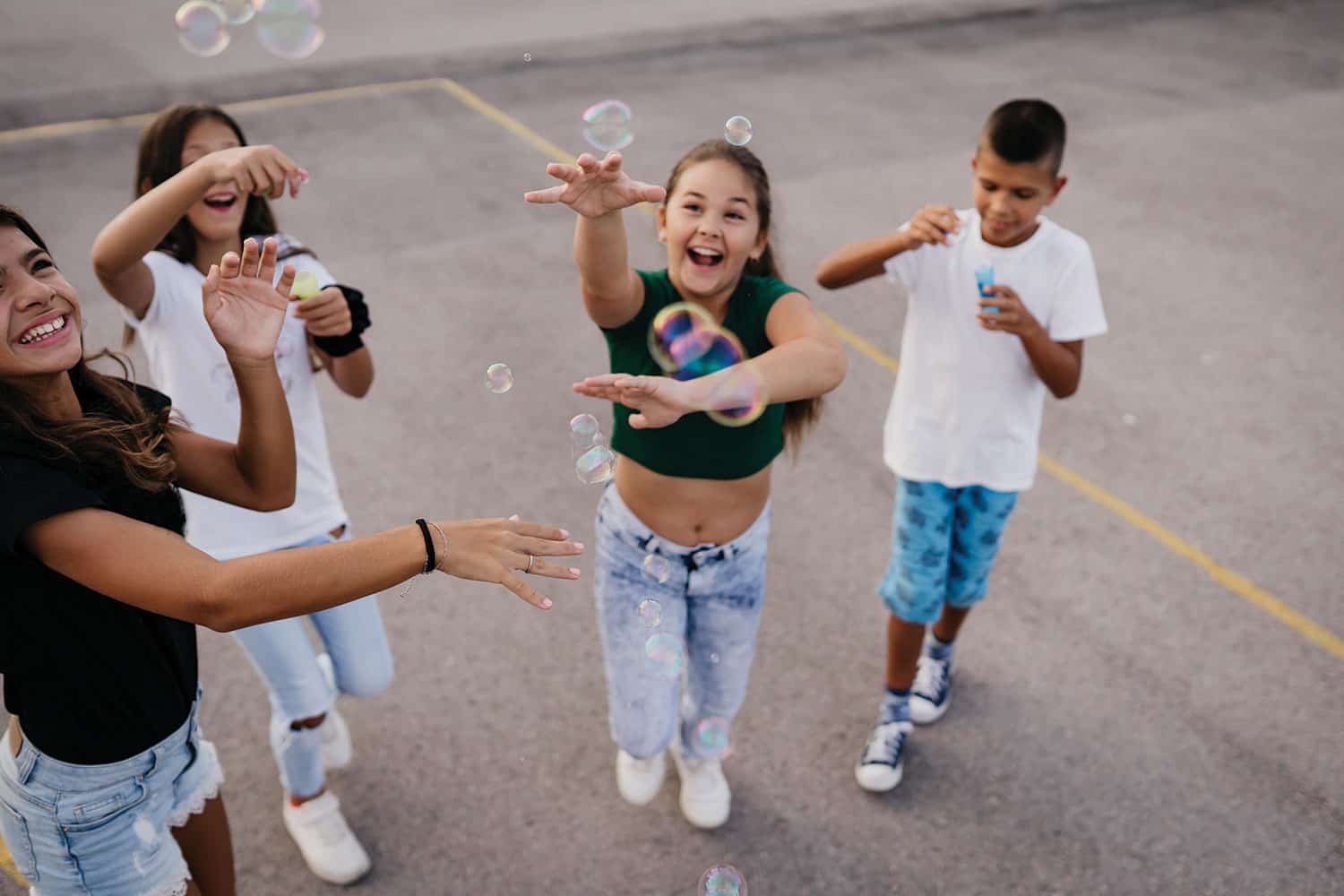 photo of smiling, laughing children playing with bubbles on a playground