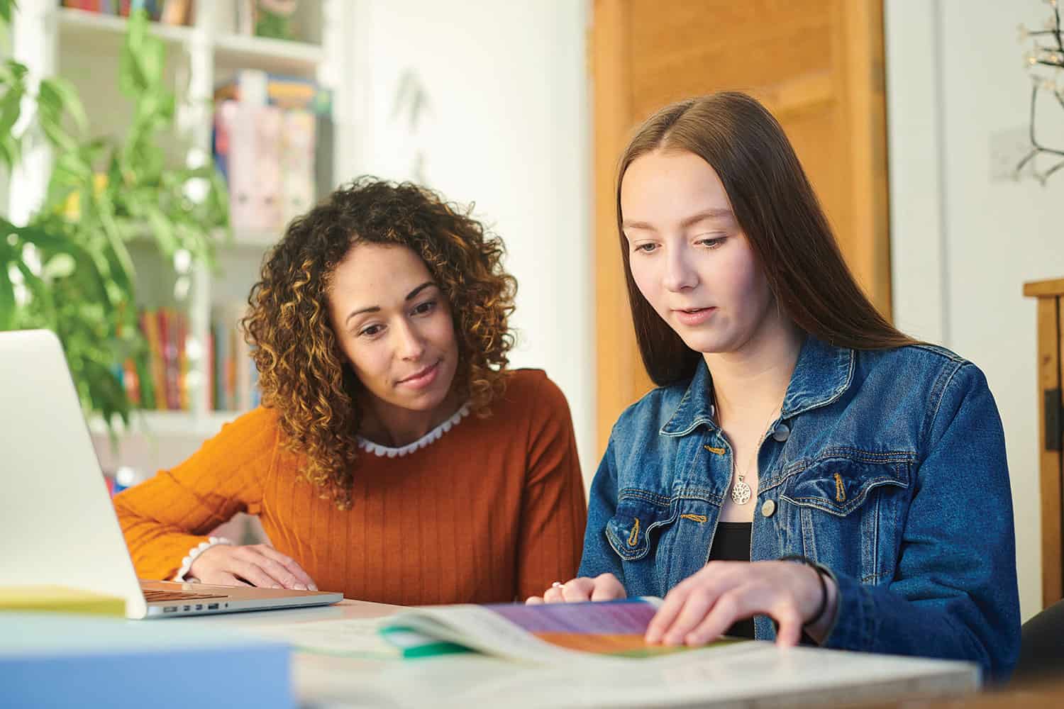 Young female care leaver looking through a university or college brochure with social worker or carer.