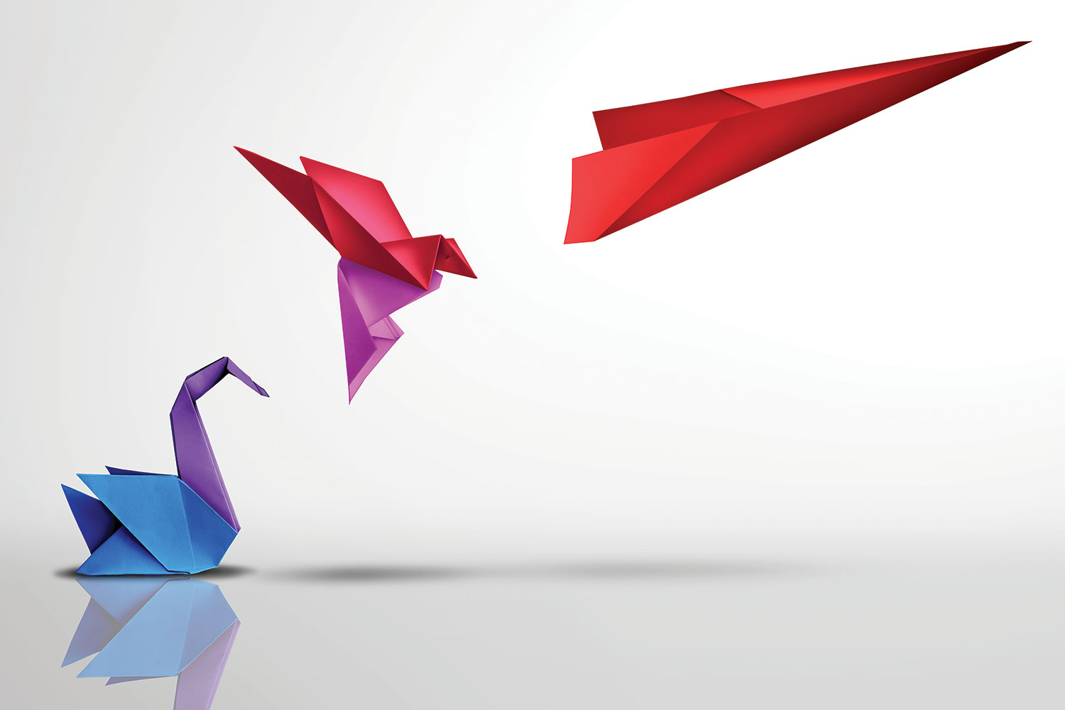 photo of colourful origami waterbird evolving upwards into a flying bird and red dart-like paper aeroplane