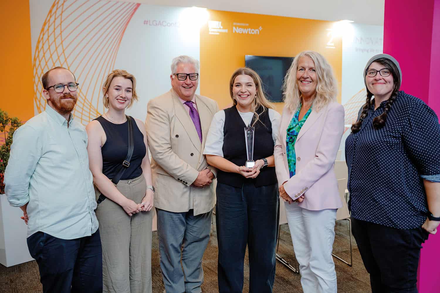 photo of Local Government Challenge winner Harriet Vitty (holding trophy), alongside Cllrs Kevin Bentley and Louise Gittins, and fellow finalists (l to r) Mike Campbell, Rebecca Dentith and Jess Finnin, in the Innovation Zone at the LGA’s annual conference in Liverpool – copyright LGA/Joe Outterside
