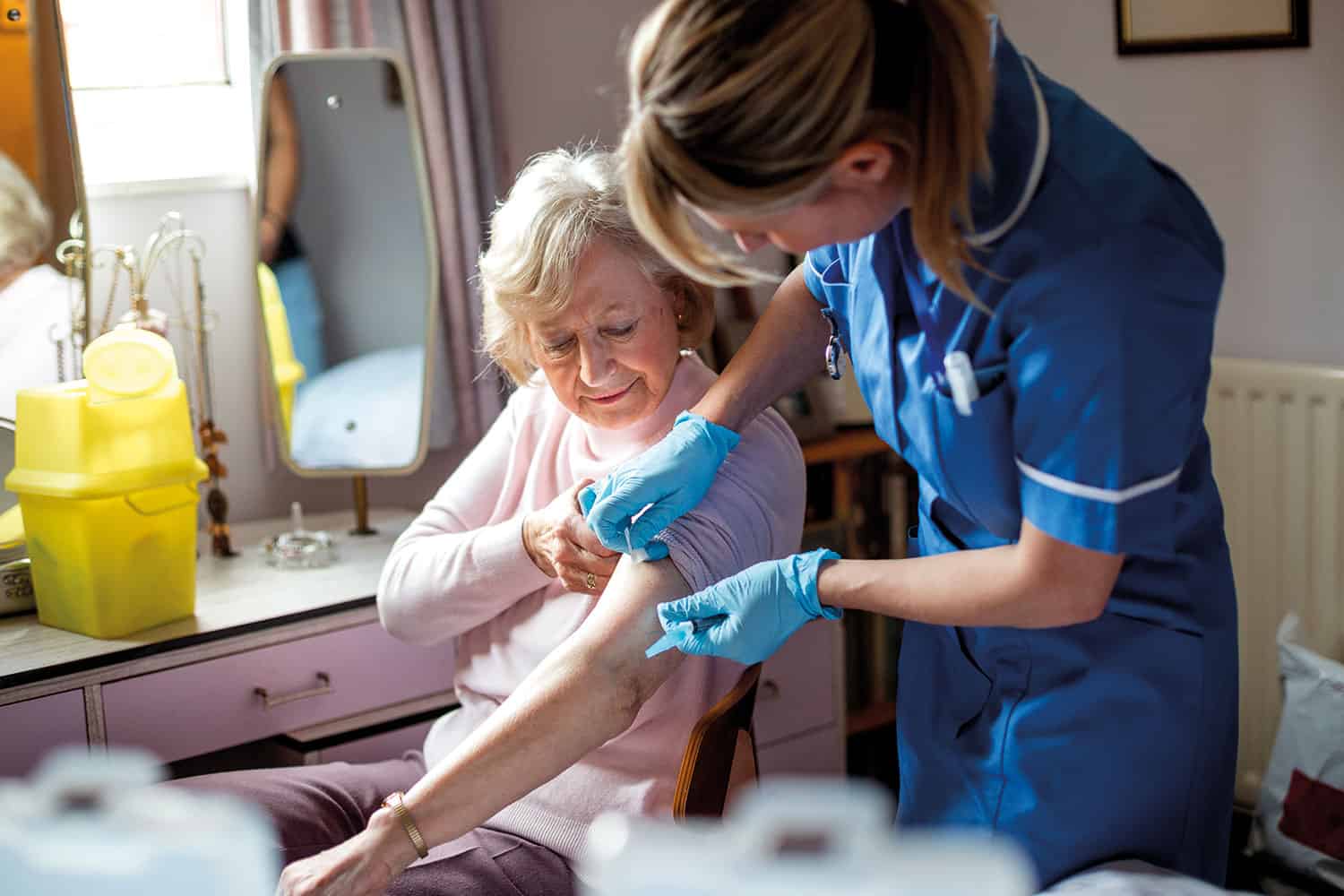 photo of nurse giving an older woman an injection in her own bedroom