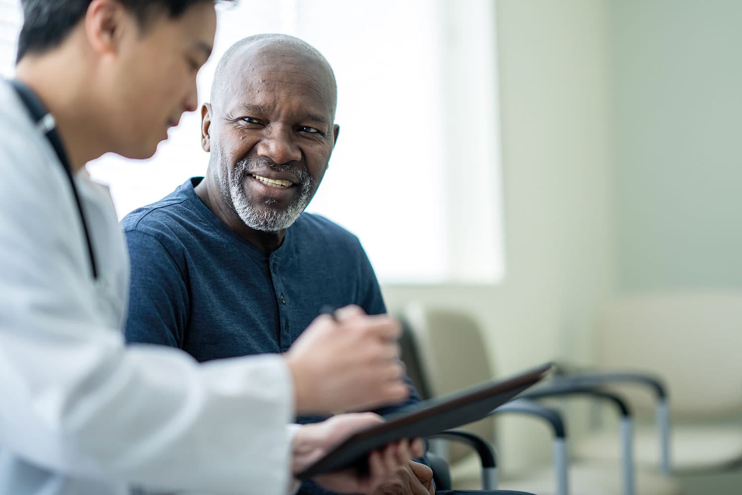 photo of medical worker talking to patient while pointing at tablet