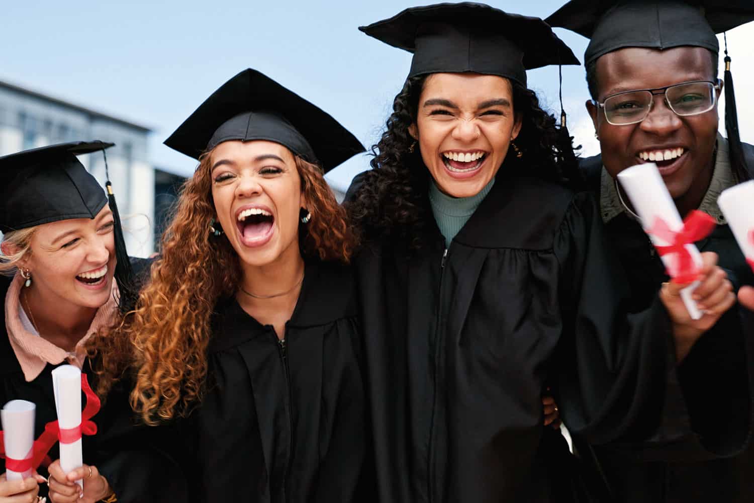 mixed group of laughing young graduates in gowns and mortar boards