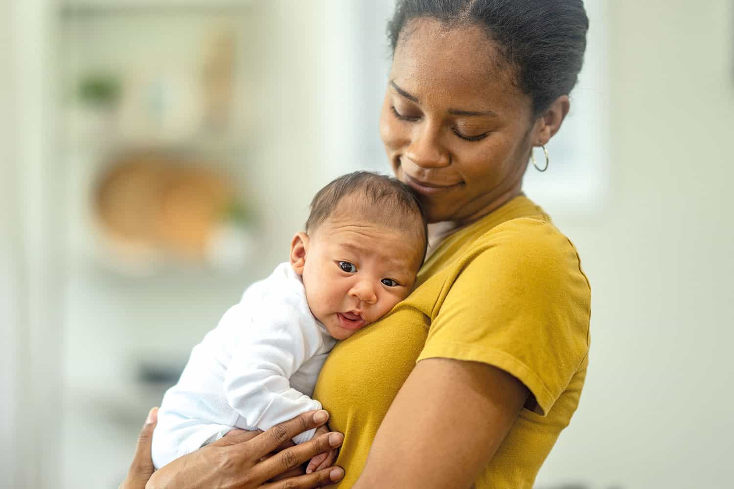 mother smiling at new baby cuddled on her chest