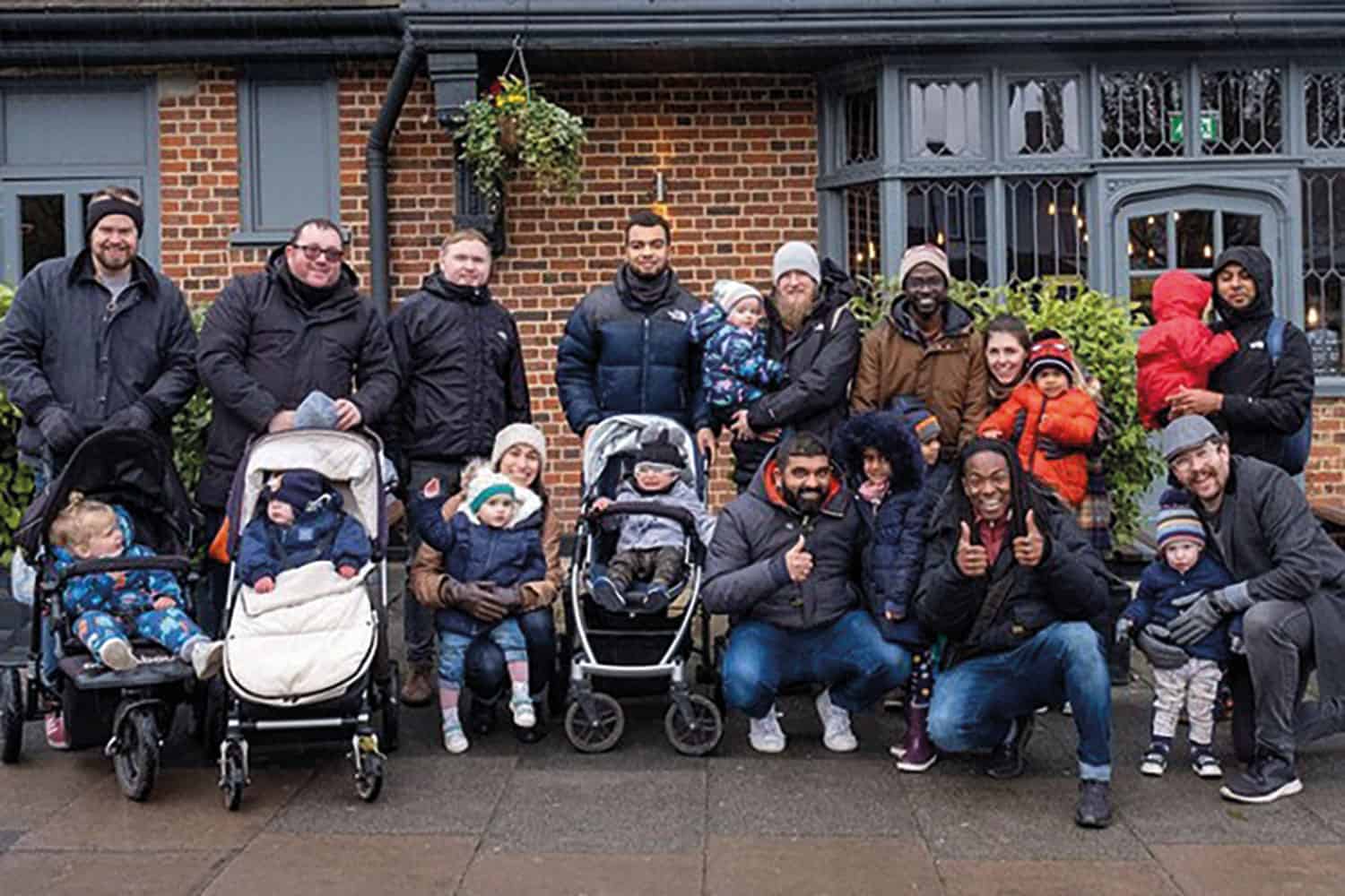 fathers from Hackney, east London, with their children in buggies, outdoor winter group shot with everyone in coats and hats