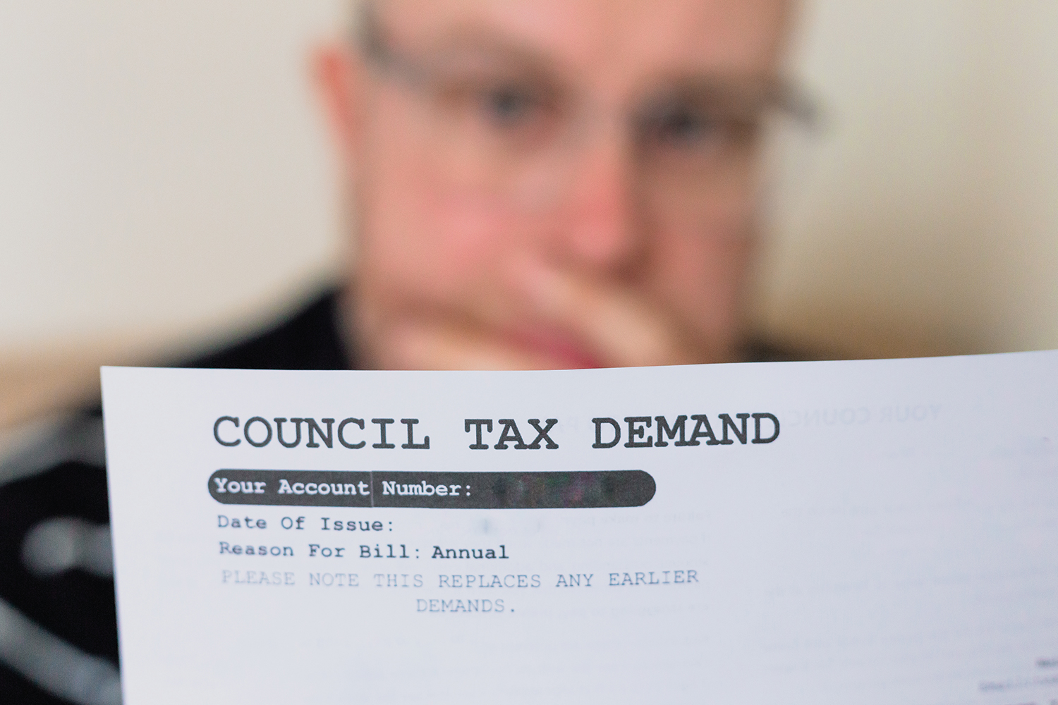 photo of an older man reading a council tax demand, focus on the letter