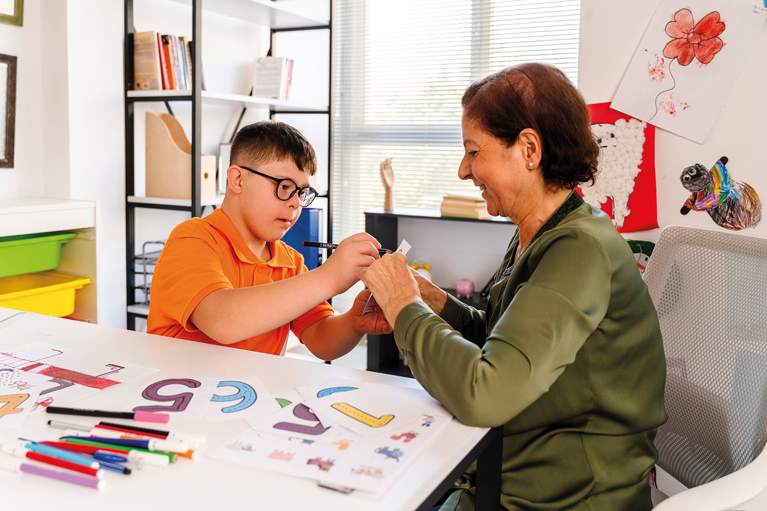 photo of young boy with SEND working one-to-one with an adult at a table in a classroom
