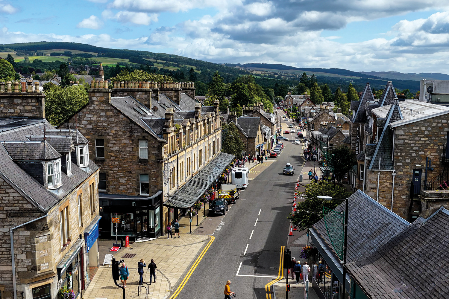 aerial shot of rural town high street surrounded by hills and trees
