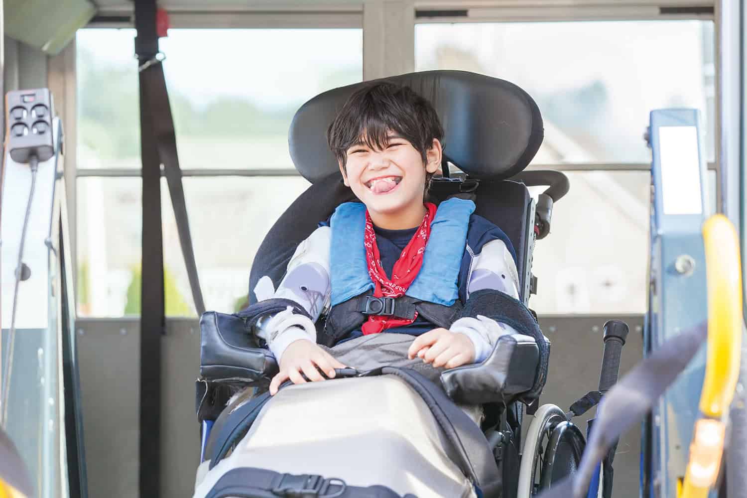 photo of smiling boy in wheelchair waiting to be helped out of a school bus