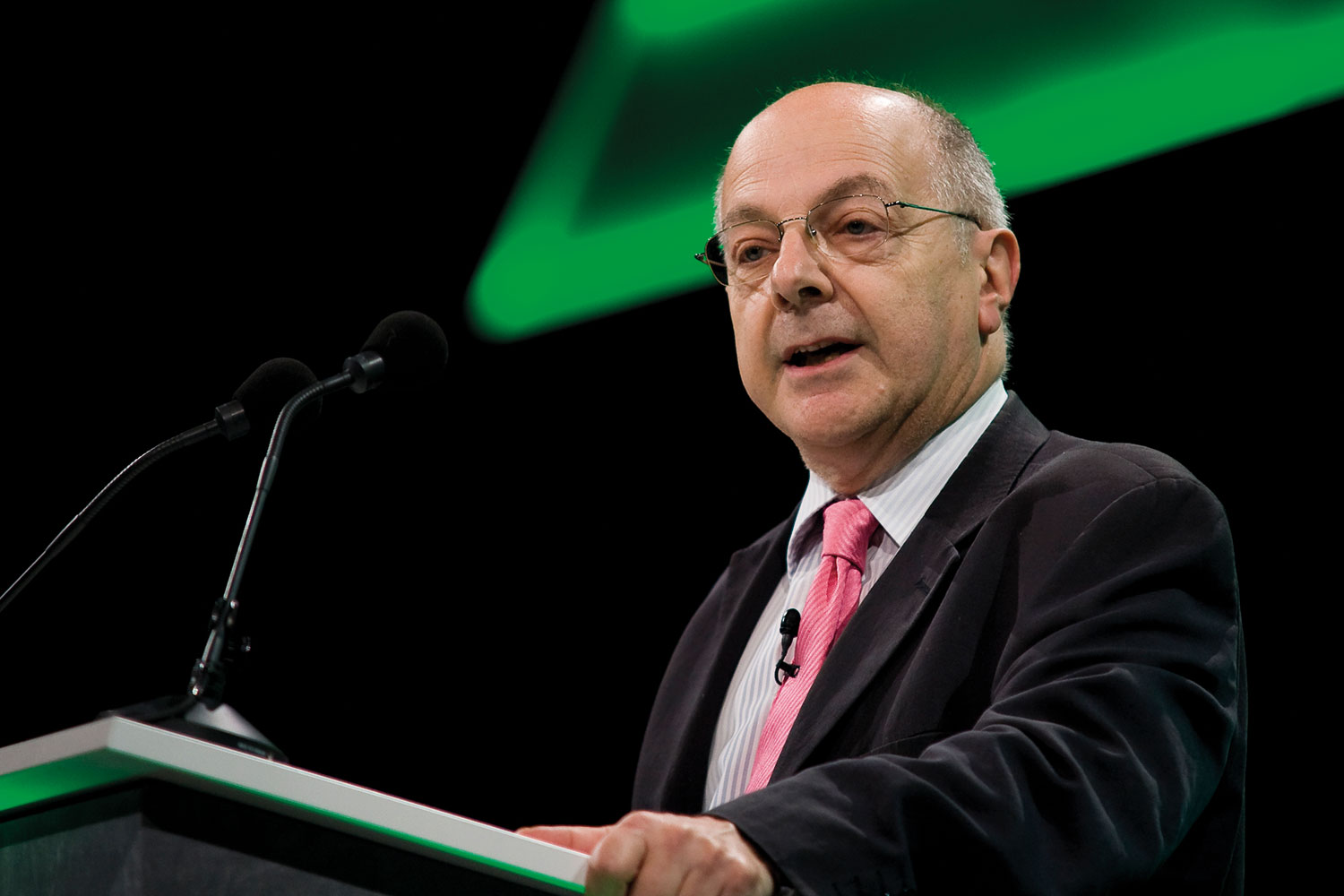 photo of Lord Jeremy Beecham in black suit and pink tie speaking at a podium against a green and black backdrop at the LGA’s annual conference in 2008