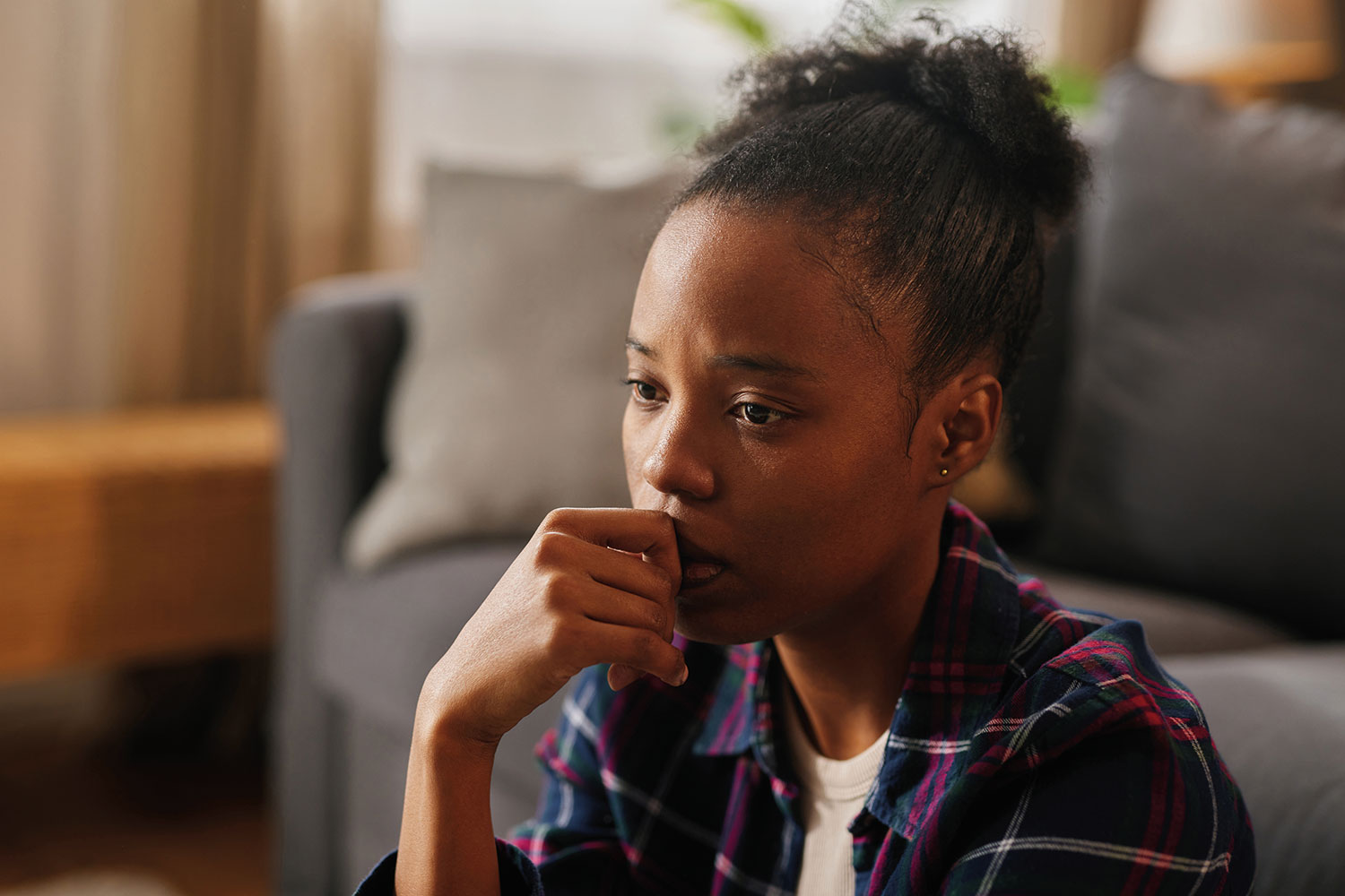 close-up photo of young woman looking pensive with her hand to her mouth