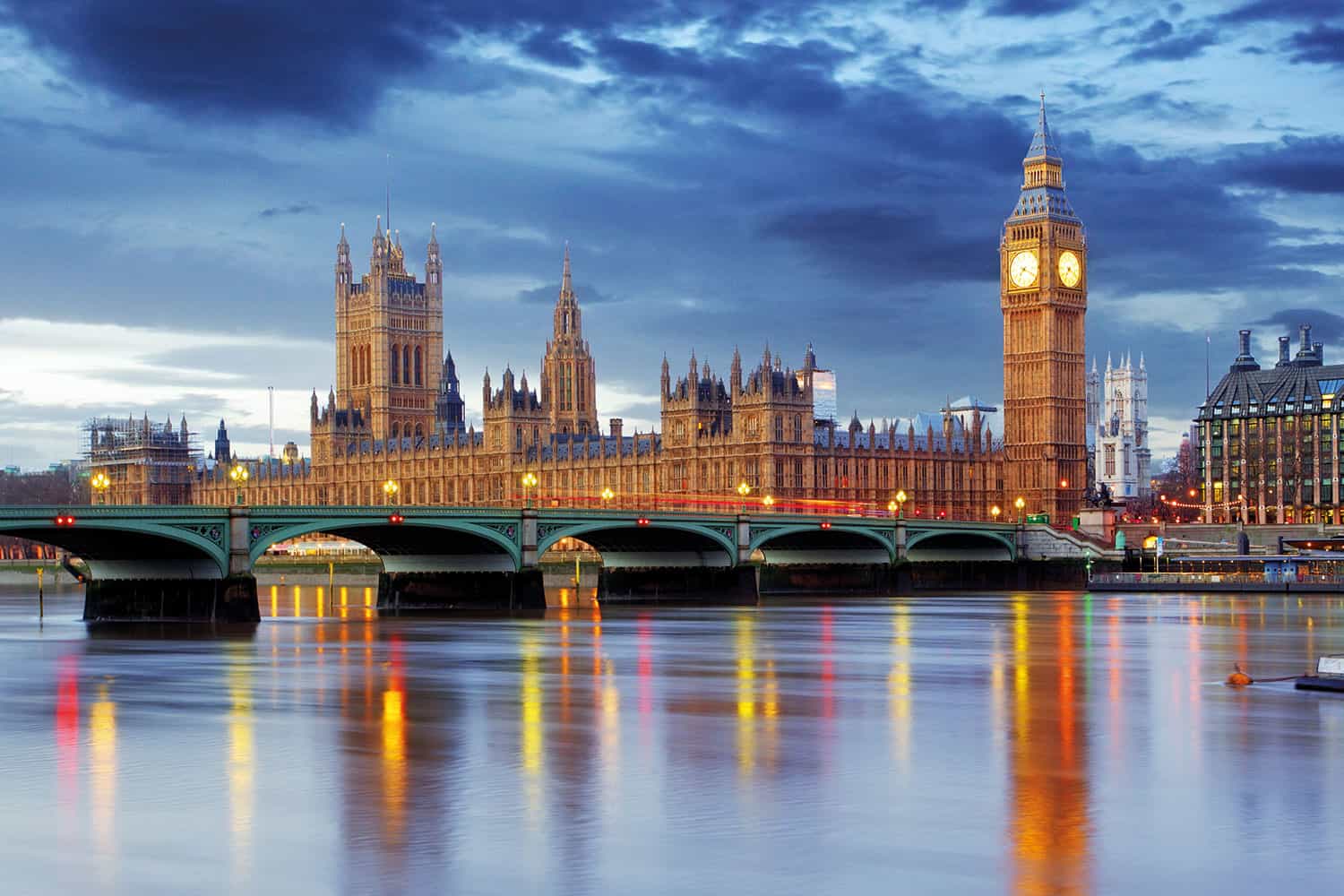 photo of Palace of Westminster and Big Ben with Westminster Bridge and the River Thames in the foreground, in the evening under cloudy skies