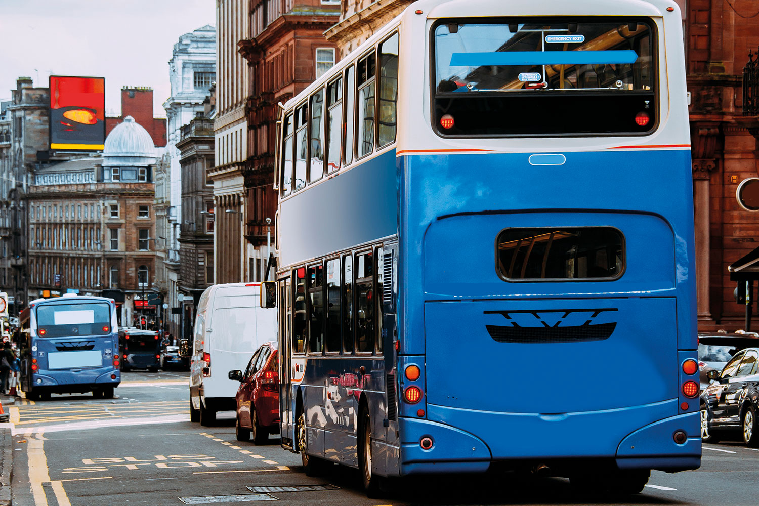 photo of blue and white passenger bus alongside a bus lane marked out in yellow, in a city centre location