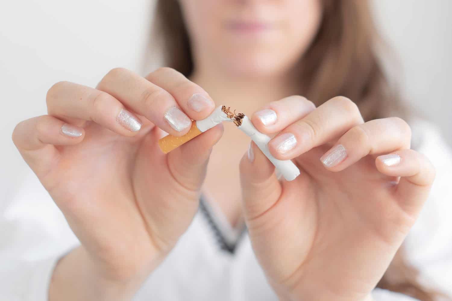photo of a woman focused on her hands snapping a cigarette in half