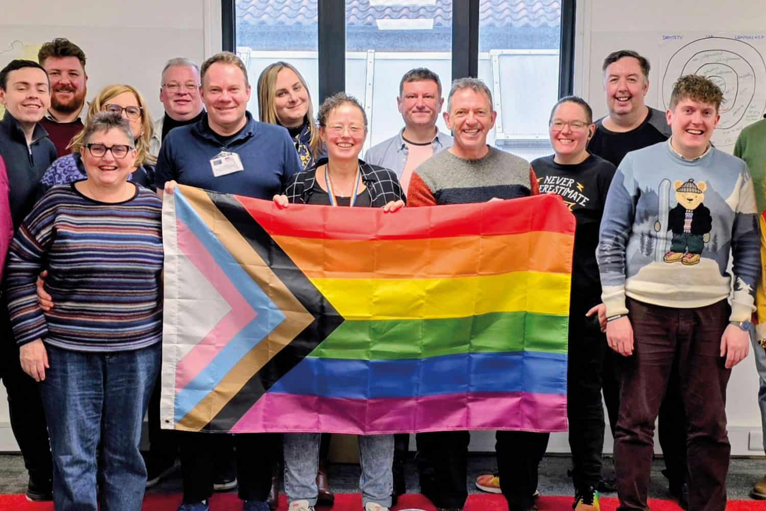 photo of group of councillors who took part in the LGA’s LGBTQ+ weekender event in early 2026, smiling and holding a large LGBTQ+ rainbow flag