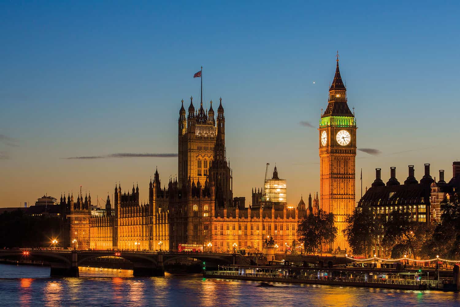 photo of Houses of Parliament from across the river, against a late twilight sky, with street lights on